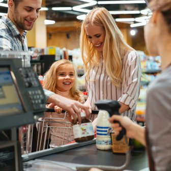 Die Familie genießt einen Einkaufstag, während sie an der Kasse stehen und die Kassiererin freundlich anlächeln.