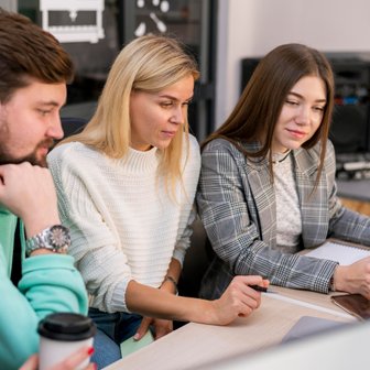In einem modernen Raum arbeiten vier junge Erwachsene zusammen, um Ideen zu entwickeln und Informationen auszutauschen.