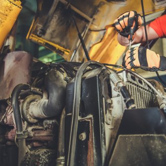Der Mechaniker ist in einer Werkstatt beschäftigt, während er mit einem Schraubenschlüssel an einem großen Motor arbeitet, um ihn zu reparieren.